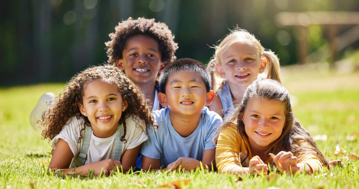 five kids laying in the grass.