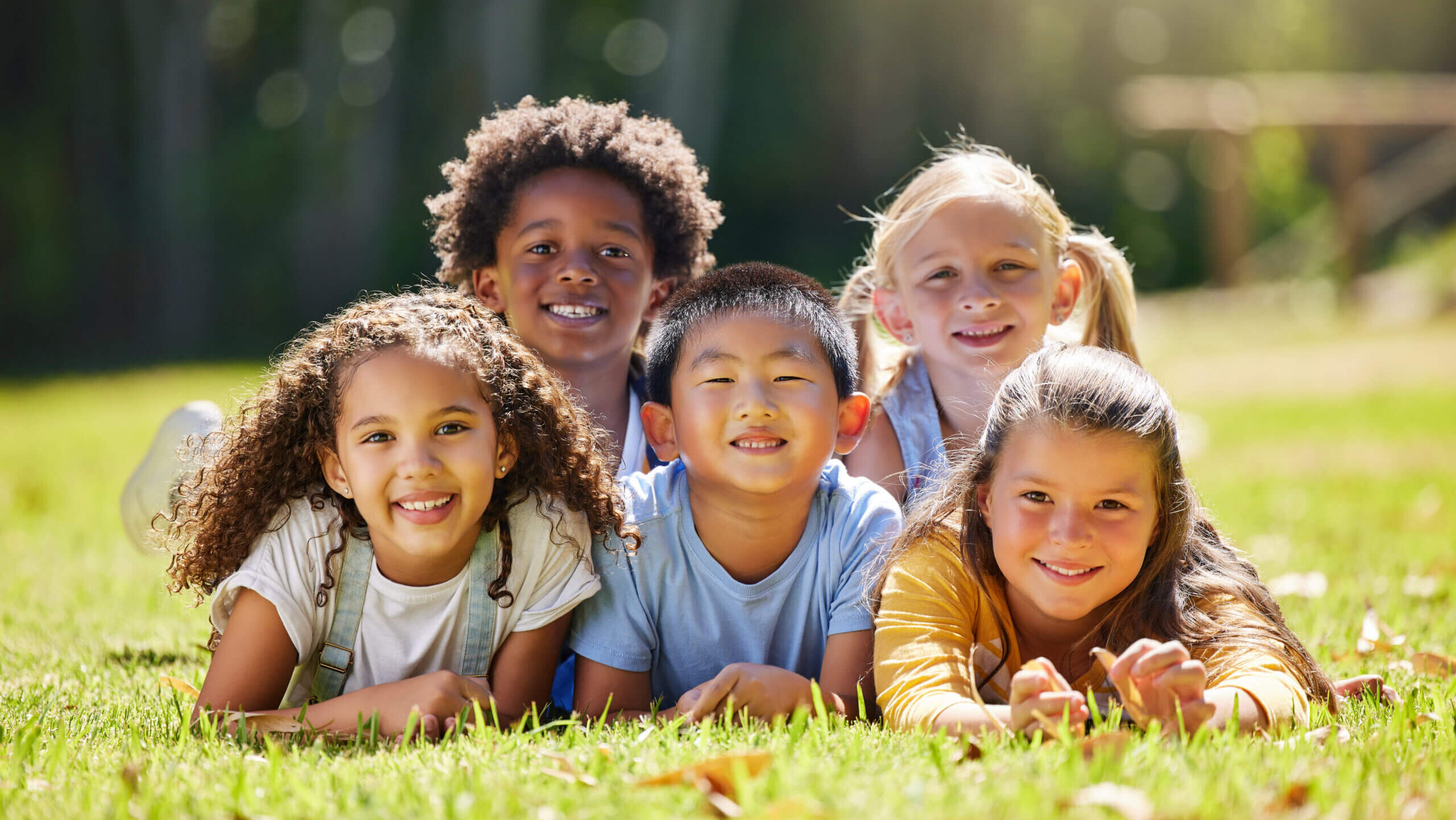 five kids laying in the grass.