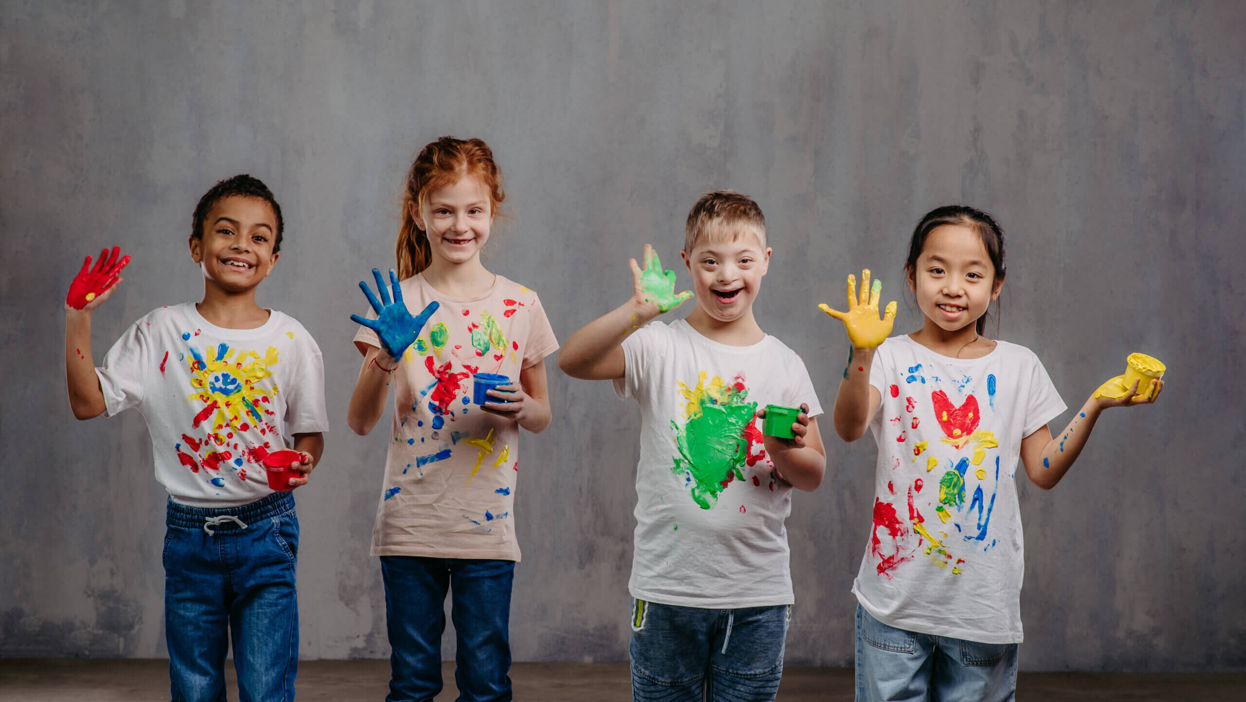 four school aged children with multicolor finger paint.