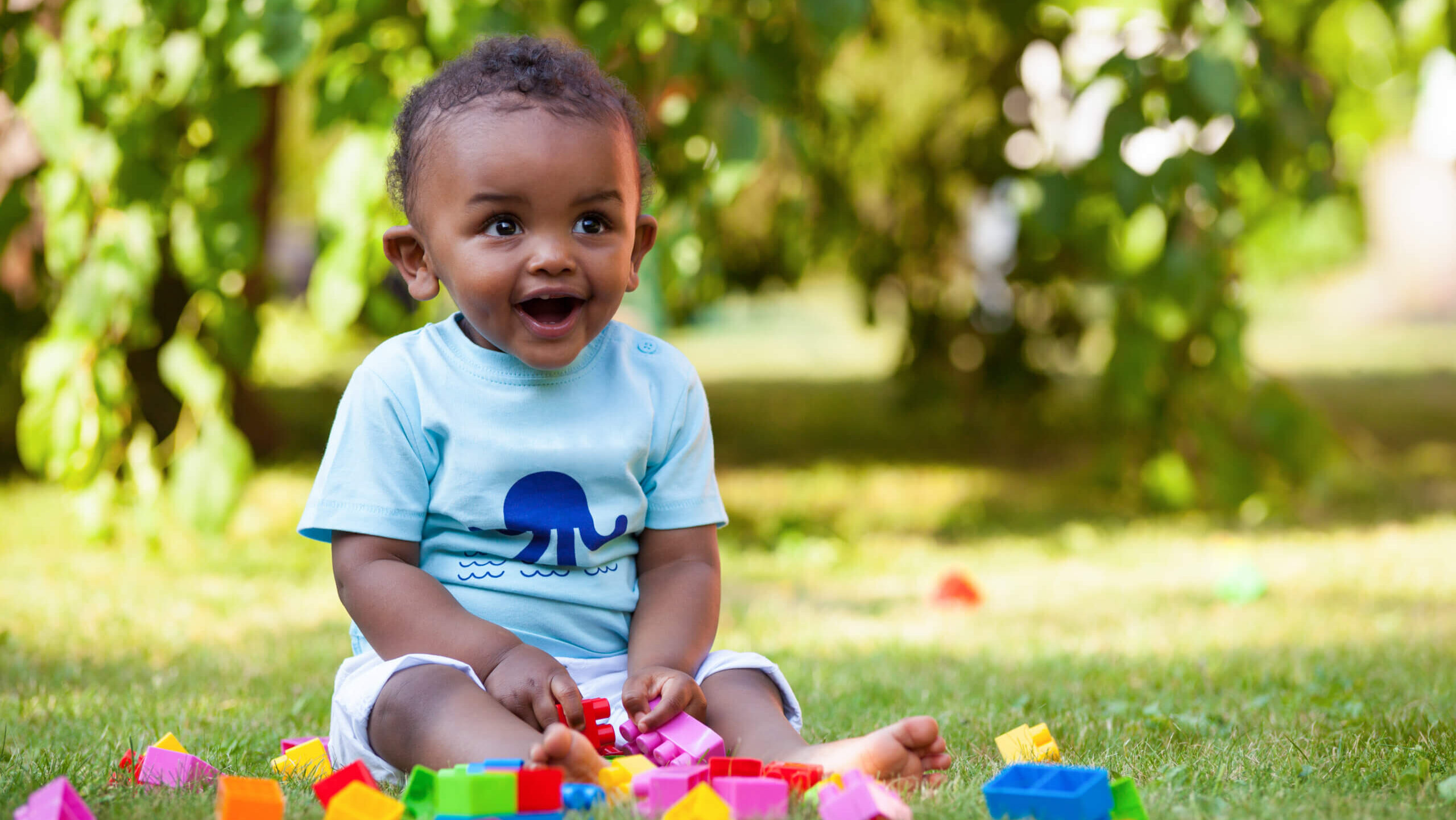 Child in park playing with colorful blocks.